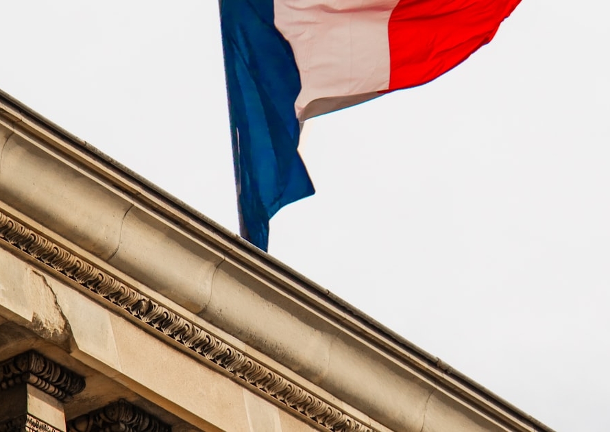 Drapeau français flottant au sommet d'un bâtiment officiel, illustrant la hausse des taxes des titres de séjour en France en 2026
