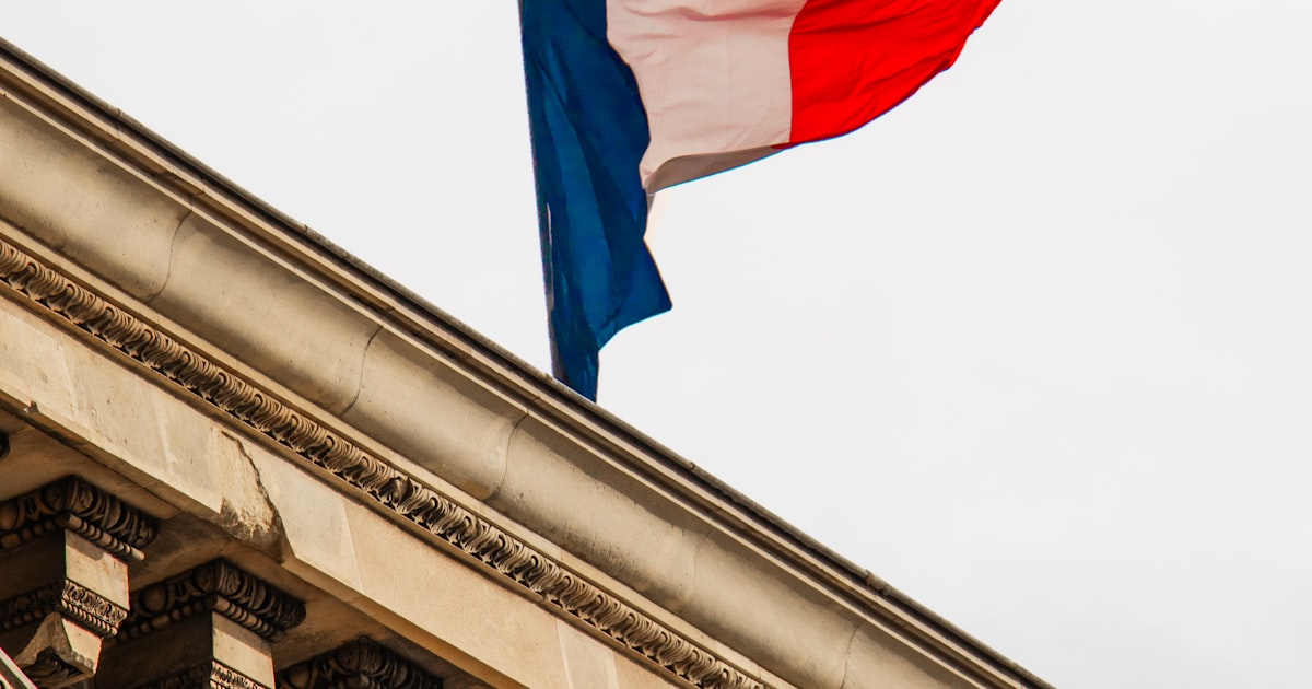 Drapeau français flottant au sommet d'un bâtiment officiel, illustrant la hausse des taxes des titres de séjour en France en 2026