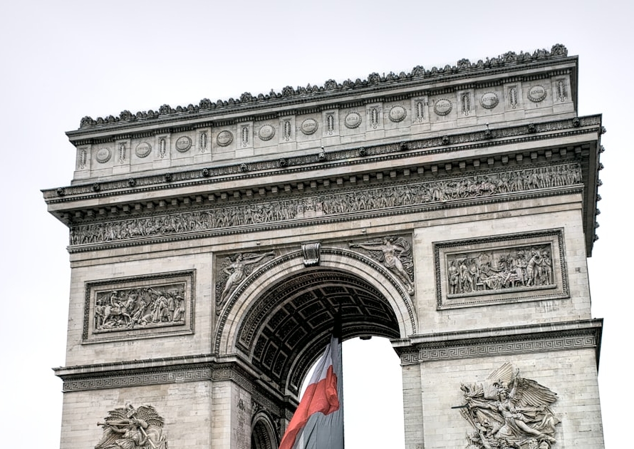 Drapeau français flottant sous l’Arc de Triomphe à Paris, illustrant la carte de séjour Talent 2026