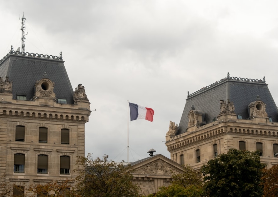 Drapeau français flottant devant un bâtiment officiel en pierre, illustrant le recours contre un refus de visa de long séjour