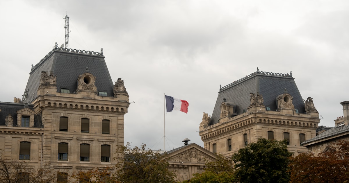 Drapeau français flottant devant un bâtiment officiel en pierre, illustrant le recours contre un refus de visa de long séjour